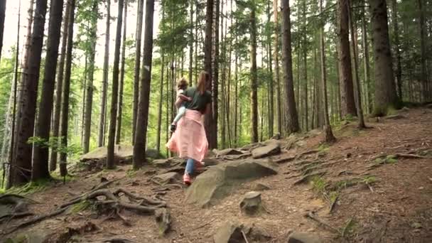 Woman holding baby girl on hands and walking in the pine forest — Stock Video