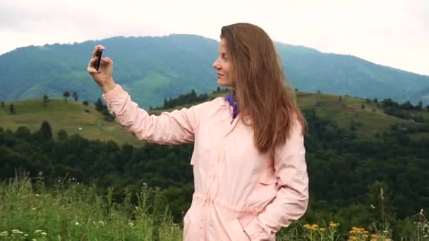 山を眺めながらスマホで自撮り写真を撮る女 — ストック動画
