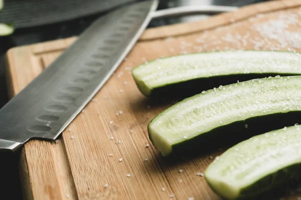 Closeup view on sliced cucumbers and knife on the wooden boaard — Stock Photo, Image