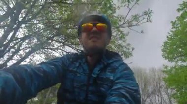 Bisikletli bir adam yağmur altında kask takıyor.