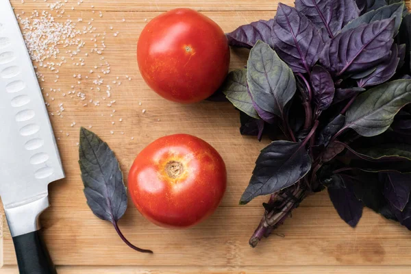 Vista superior en par de tomates rojos y hojas de albahaca — Foto de Stock