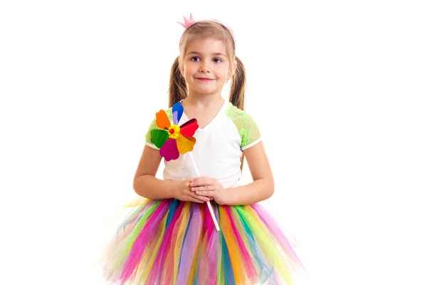 Klein meisje in kleurrijke rok en windmolen speelgoed kijken in camera — Stockfoto