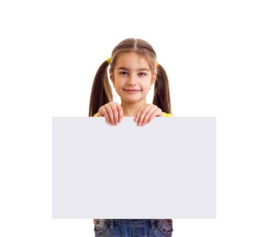 Küçük gülümseyen kız kameraya bakıyor ve elinde beyaz kağıt pankart tutuyor.