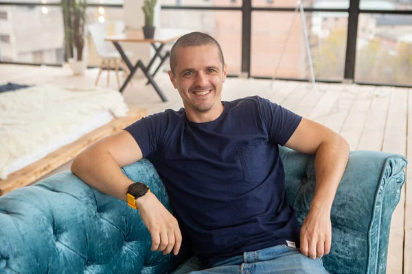 Retrato del hombre sonriente mirando en la cámara sentado en el sofá — Foto de Stock