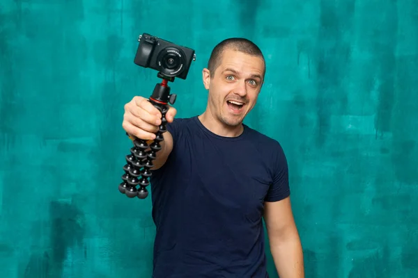 Homem feliz segurando câmera no tripé e olhando na câmera — Fotografia de Stock