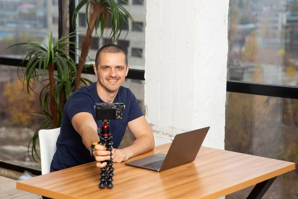 Smiling man blogger holding camera in tripod