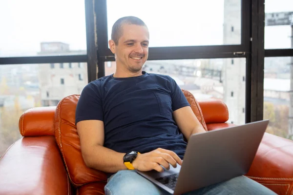 Glimlachende man die werkt op laptop en op het scherm kijkt — Stockfoto