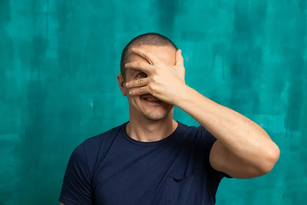 Man sluit zijn gezicht met handpalm, maar kijkt met een oog — Stockfoto