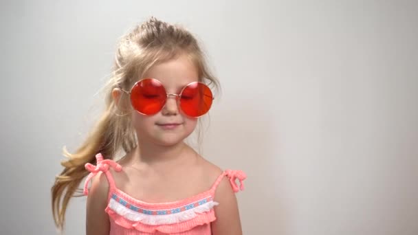 Alegre engraçado pouco encaracolado menina se divertindo em óculos vermelhos e olhando na câmera — Vídeo de Stock