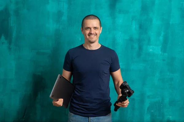 Homme souriant avec caméra et ordinateur portable dans les mains — Photo