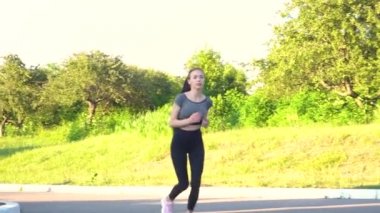 Genç bayan şehir parkında açık havada koşuyor..