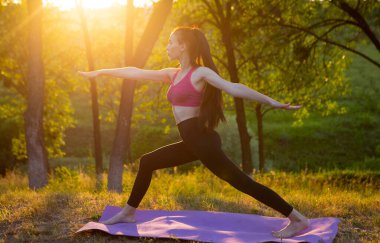 Kadın arka planda güzel doğa üzerinde egzersiz yapıyor.