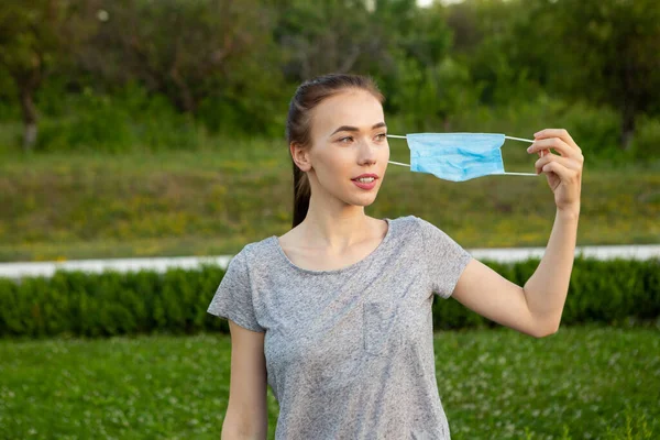 Jonge vrouw neemt medisch masker af en ademt diep en glimlachend opzij kijkend. Rechtenvrije Stockfoto's