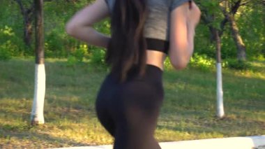 Şehir parkında açık havada koşan genç bir kadının arka planı egzersiz yapıyor..