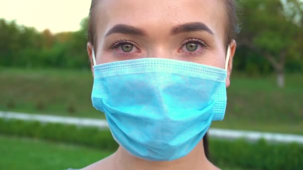 Kobieta w ochronnej masce medycznej patrząc przed kamerą. — Wideo stockowe