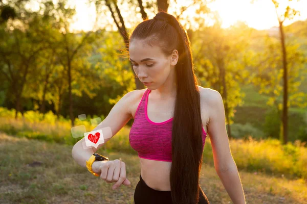 Mujer deportiva de salud que usa un dispositivo de reloj inteligente con icono de salud y forma de corazón —  Fotos de Stock
