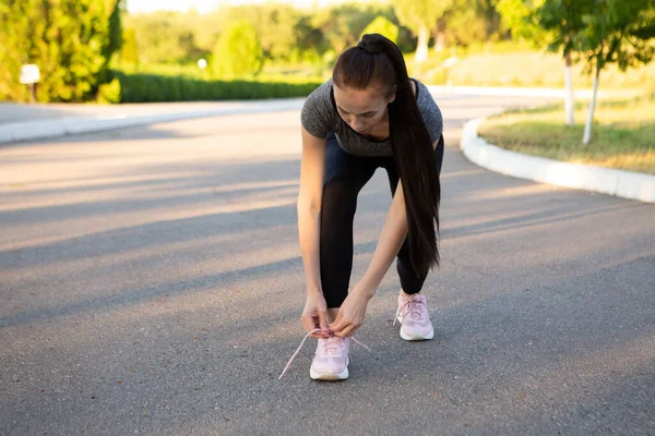 Sportlerin schnürt im Sommer vor dem Lauf ihre Schnürsenkel. — Stockfoto