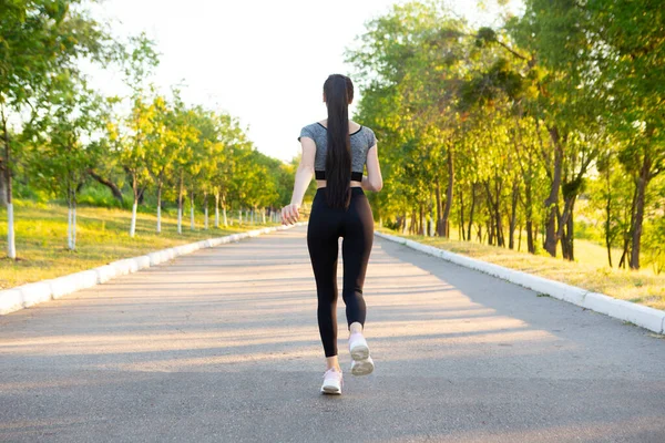 Back view on running sporty woman in the park on road. — Stock Photo, Image