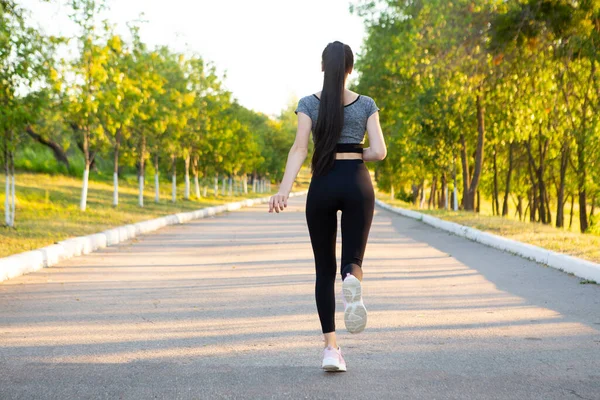 Vista sobre la espalda de una atleta corriendo en el parque . —  Fotos de Stock