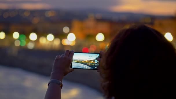 Mujer tomando fotos de la ciudad nocturna usando un teléfono inteligente. Bonito, Francia. 4K, UHD — Vídeos de Stock