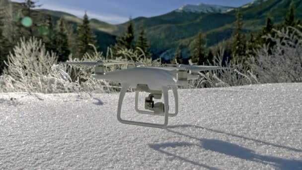 Cena de câmera lenta de um drone pendurado no ar logo acima do chão nevado nas montanhas de inverno. Tiro conceito paisagem inverno — Vídeo de Stock