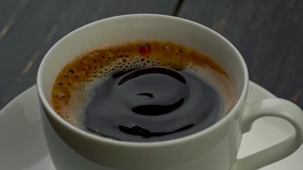 Gotas de café cayendo en una taza de café, cubierto con espuma apetitosa. Movimiento lento — Vídeos de Stock