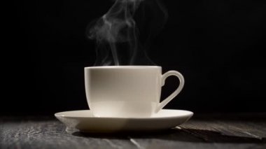 Koyu ahşap arka plan üzerinde dumanı tüten kahve fincanı. UHD, 4k