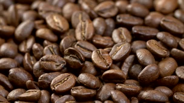 Kaffebönor bakgrund. Nära upp skott av roterande rostade kaffebönor. 4k Uhd — Stockvideo