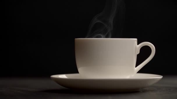 Vapor lentamente subindo de uma xícara de café quente. Fundo escuro — Vídeo de Stock