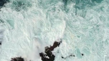 Köpüklü dalgalar bir kayalık sahil tarafından fırtınalı okyanus kaynar. Yukarıdan aşağı hava atış, Uhd