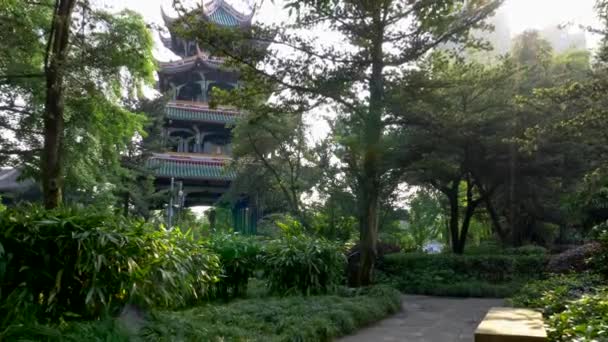 Chengdu, Sichuan, China. Torre Wangjiang Pabellón de Wangjiang y exuberante flora verde. Rayos brillantes de sol que vienen a través de los árboles en el Wangjiang Pavilion Park. La torre está al fondo. 4K — Vídeo de stock