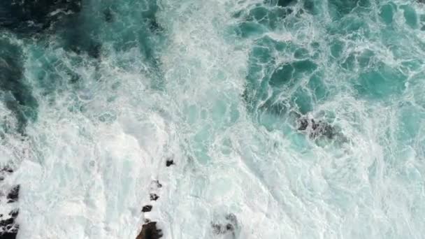 Olas tormentosas feroces, cubiertas de espuma, golpeando la costa rocosa con gran poder. Furioso océano de color turquesa disparado desde arriba. plano aéreo, UHD — Vídeo de stock