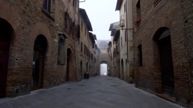 San Gimignano, İtalya. Ortaçağ şehrin dar bir sokakta yürürken, aura ile eski kez dolu. Caddenin her iki tarafında eski tuğla duvarlı binalar vardır. 4k