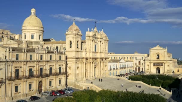 Noto, Sicilya, İtalya. Arka planda öğleden sonra güneş ve mavi bulutlu gökyüzü Noto katedralde. 18. yüzyılda tarzı Sicilya Barok katedral inşa edilmiştir. UHD — Stok video