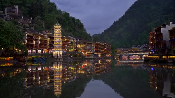 Traditionele Chinese toren en huizen aan beide oevers van de rivier met nacht verlichting tijdens de schemering. De oude stad van Fenghuang County, China. Fenghuang betekent Phoenix Chinese zangvogels. Panoramisch — Stockvideo