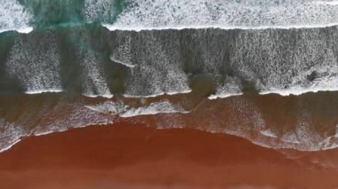 Okyanus kıyısında arka plan. Köpüklü dalgalar turkuaz okyanusun kahverengi bir kum Beach'e geliyor. Yukarıdan aşağı atış, Uhd