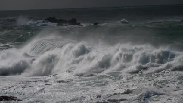 Большие океанские волны. Яростный штормовой океан массивно бьет своими пенными волнами по скалистому побережью. UHD — стоковое видео