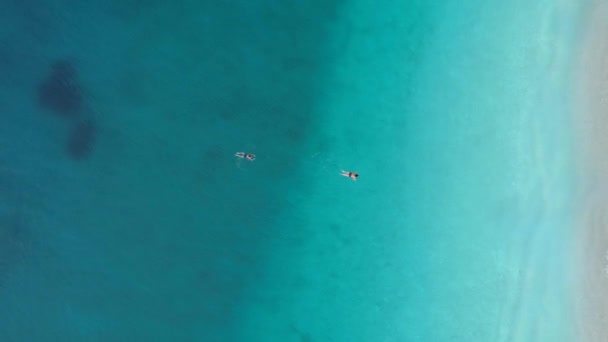 Hombre y mujer nadando en el agua turquesa clara y transparente del mar Mediterráneo. Disparo aéreo, 4K — Vídeos de Stock