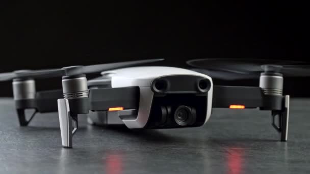 Compact drone quadcopter dengan kamera digital, mesin menyala. Dengan latar belakang hitam. 4K UHD — Stok Video