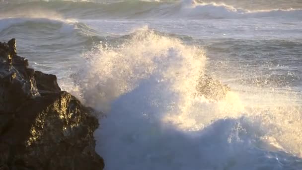 Ondas oceânicas furiosamente esmagando contra rochas ao pôr-do-sol. A água espirra lentamente caindo no chão sob as luzes do pôr do sol. Tiro em câmara lenta — Vídeo de Stock