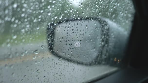Aspettando che la pioggia si fermi dentro un'auto. La finestra laterale del è coperta con gocce d'acqua. La finestra di marcia e il traffico di passaggio sono visti attraverso la finestra. 4K — Video Stock