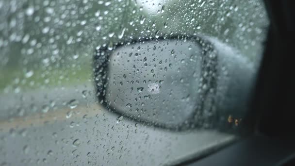 Esperando hasta que la lluvia se detenga dentro de un coche. Ventana lateral de la está cubierta con gotas de agua. La ventana trasera y el tráfico de paso se ven a través de la ventana. 4K — Vídeos de Stock