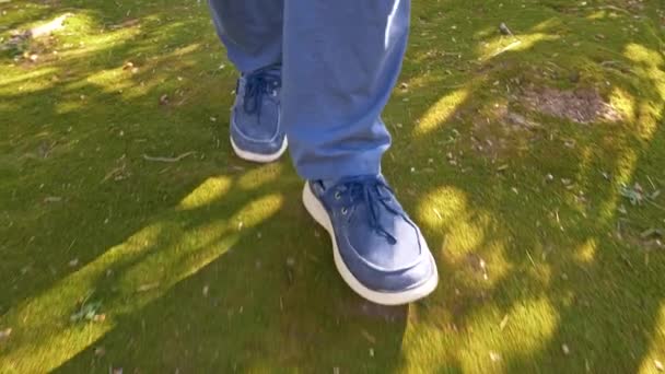Muž v modrém džínové Jean botách na zeleném mechu v parku — Stock video
