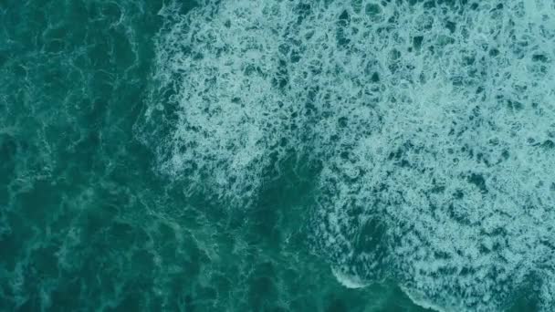 Foamy waves rolling turquoise beautiful transparent waters of an ocean or sea. Aerial top down shot, UHD — Stock Video