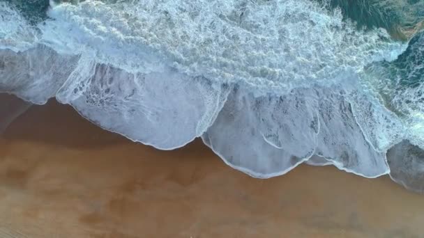 Onde schiumose in arrivo sulla spiaggia sabbiosa. Costa portoghese dell'Oceano Atlantico. Ripresa aerea dall'alto verso il basso, 4K — Video Stock