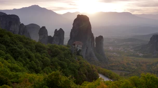 Meteora acantilados rocosos y un valle durante la puesta del sol en Tesalia, Grecia. Aquí se encuentra uno de los complejos más importantes de los monasterios ortodoxos orientales. Un disparo panorámico. 4K — Vídeo de stock