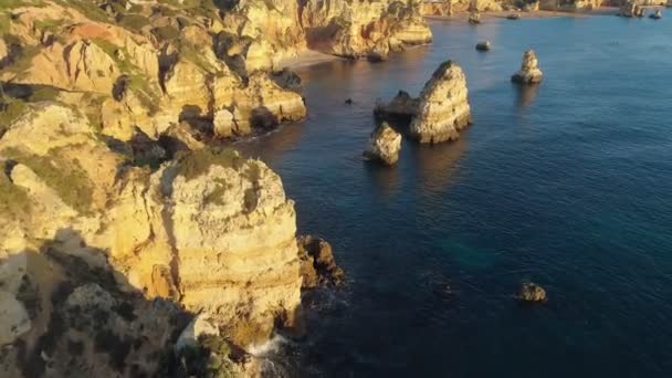 Algarve, Portugal. Vliegen over turquoise wateren van de Atlantische Oceaan en gele rotsen aan de kust tijdens zonsopgang. Luchtfoto, 4k — Stockvideo