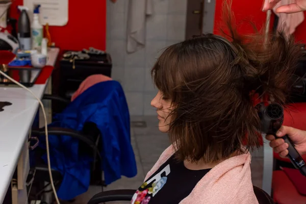 Young girl having a hair dry in the salon while doing a hair cut.