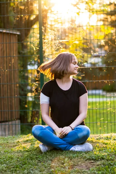 Chica joven con nuevo peinado corto sentado en el parque con hermoso fondo Imagen de archivo