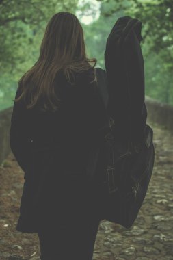 Genç kız naure içinde yürürken gitar çantası taşıyor. Bayan gitarist gitaristle seyahat eder ve güzel manzaranın tadını çıkarır.